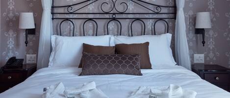 A neatly made bed with white and brown pillows, a metal headboard, and two bedside tables with lamps.