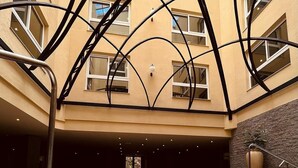 Un jacuzzi en un área de piscina interior de varios niveles, con un diseño arquitectónico moderno, incluyendo una estructura de techo única y una pared de piedra.