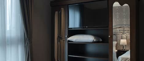 Una habitación de hotel con un armario grande, una cama y una mesita de noche con lámpara.