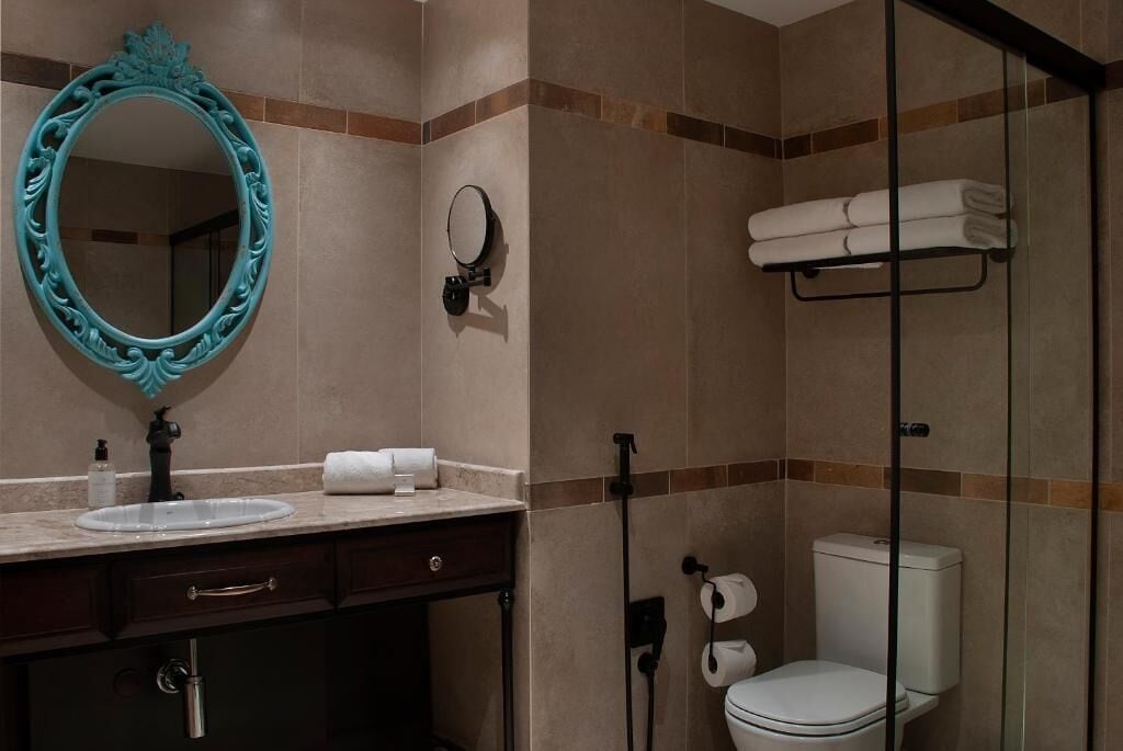 A bathroom with a vanity, a large mirror, a toilet, and a glass shower enclosure.