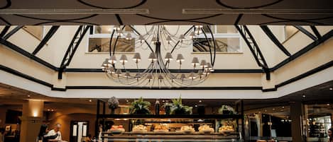 A buffet area with multiple food stations and a modern chandelier.