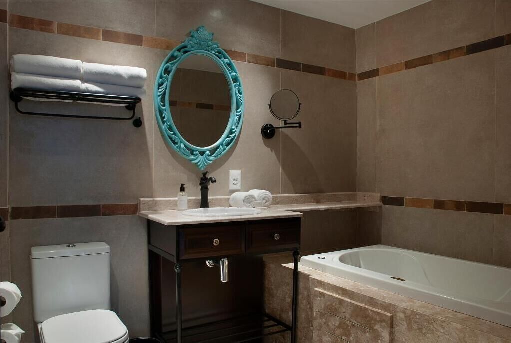 A bathroom with a white toilet, a sink with a mirror, and a bathtub.