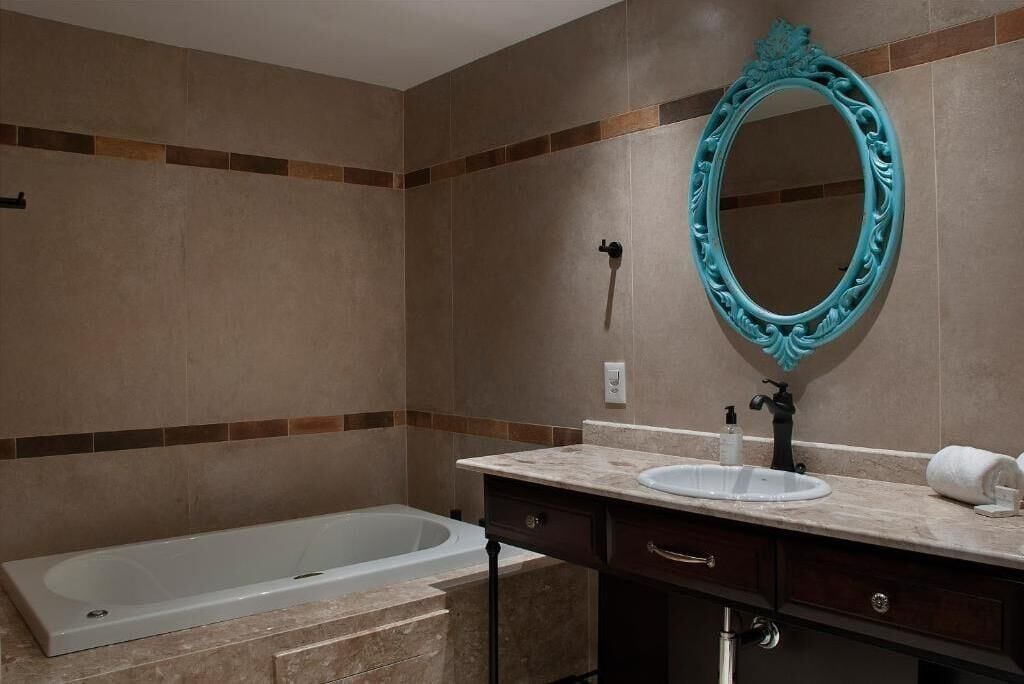 A bathroom with a bathtub, a sink, a mirror, and a towel.
