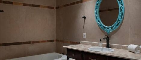 A bathroom with a bathtub, a sink, a mirror, and a towel.