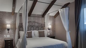 Uma cama com dossel coberta com lençóis brancos, duas luminárias de cabeceira e uma mesa de cabeceira com abajur.