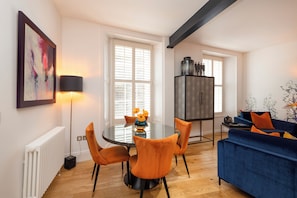 A dining area with a round table, orange chairs, and a vase with flowers.