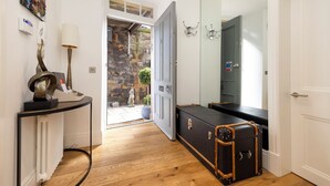 A hallway with a radiator, a lamp, a dog statue, a suitcase, and a door. - Edinburgh Luxury Apartment- The Matisse Suite (Edinburgh)