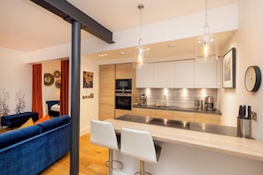 A modern kitchen with a central island, stainless steel appliances, and pendant lighting.