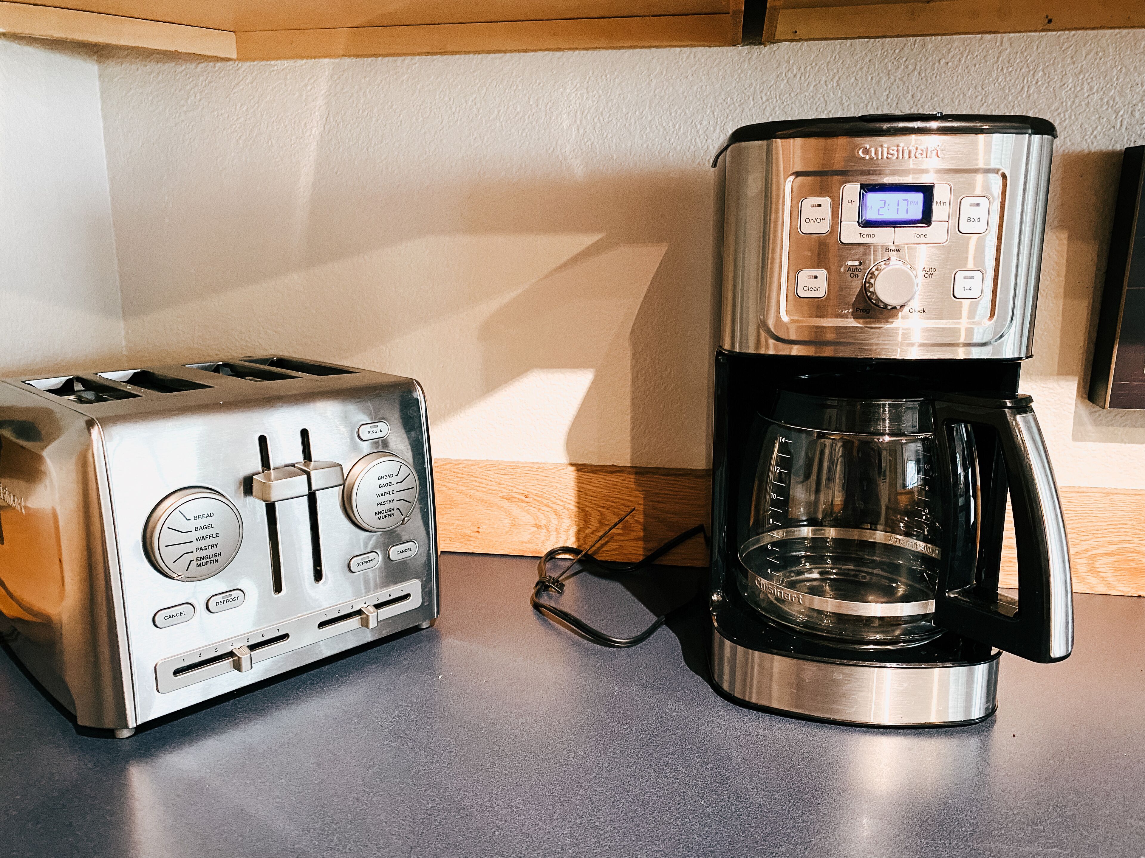 Ruostumattomasta teräksestä valmistettu leivänpaahdin ja Cuisinart-merkkinen kahvinkeitin keittiön työtasolla.