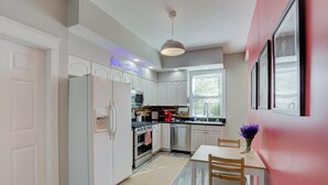 Een moderne keuken met witte kastjes, een roestvrijstalen koelkast, een inbouwoven en een koffieapparaat.