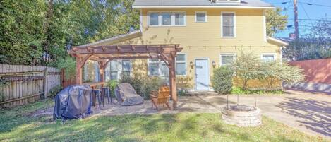 A two-story yellow house with a covered patio and a fire pit.