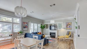 Een moderne woonkamer met een blauwe bank, een witte eettafel en een open haard.