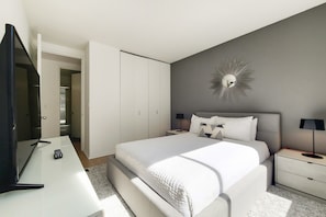A bedroom with a bed, bedside tables, a TV, and a wardrobe.