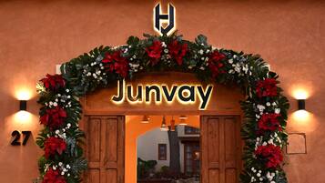 A hotel entrance with a wooden facade, a sign reading "Junway", and a decorative floral arch.