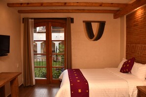 Une chambre à coucher avec un lit, un téléviseur fixé au mur et une vue sur l’extérieur grâce à une porte vitrée.