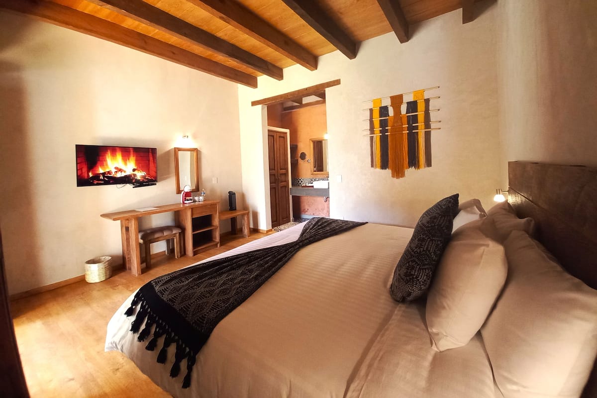 Un dormitorio con cama, escritorio, espejo y televisor montado en la pared.