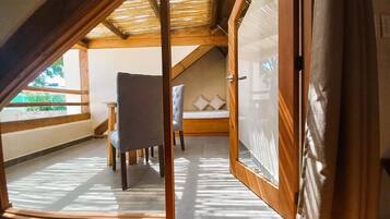A room with a sloped ceiling, a bed, a chair, and a table.