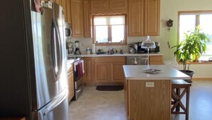 A kitchen with wooden cabinets, a stainless steel refrigerator, a sink, and a window. - 1 level Golf Course Property think Golf/Hunting/Fishing/ATV’s/Snowmobiling (Mondovi)