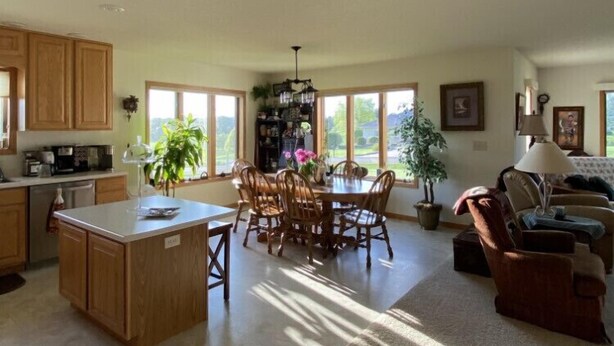 A spacious kitchen with wooden cabinets, a dining area with a large table and chairs, and a cozy living room with a sofa and a lamp. - 1 level Golf Course Property think Golf/Hunting/Fishing/ATV’s/Snowmobiling (Mondovi)