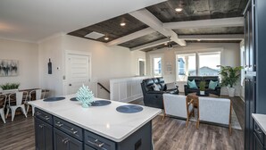 A modern kitchen with a central island, dark cabinetry, and a rustic ceiling.
