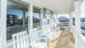 A covered outdoor deck with white chairs and a view of the surrounding area.