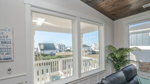 A room with a large window overlooking a deck and houses.