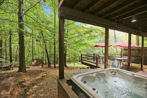 Ein Whirlpool inmitten von Wald mit einer Holzdiele und einem Picknicktisch.