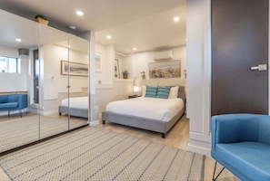 A modern bedroom with a large bed, a blue armchair, and a glass partition. - Stunning Ocean & Coastal Views ~Close to all (La Jolla)