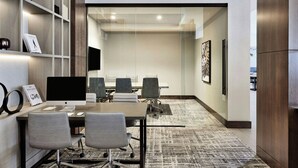 A modern conference room with a large table, four chairs, a computer, and a bookshelf with books and a framed picture. - AC Hotel by Marriott St. Louis Chesterfield (Chesterfield)