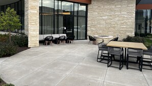 An outdoor patio area with a stone wall, seating, and a table. - AC Hotel by Marriott St. Louis Chesterfield (Chesterfield)