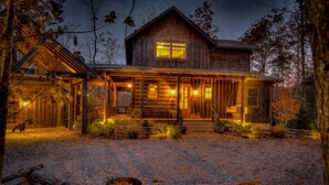 A rustic cabin with a front porch, a fireplace, and a gravel driveway. - Singing Pines - Mountain Views | Hot Tub | Screened Porch | Fire Pit (Blue Ridge)