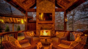 A cozy outdoor seating area with wicker furniture and a central wood-burning stove. - Singing Pines - Mountain Views | Hot Tub | Screened Porch | Fire Pit (Blue Ridge)
