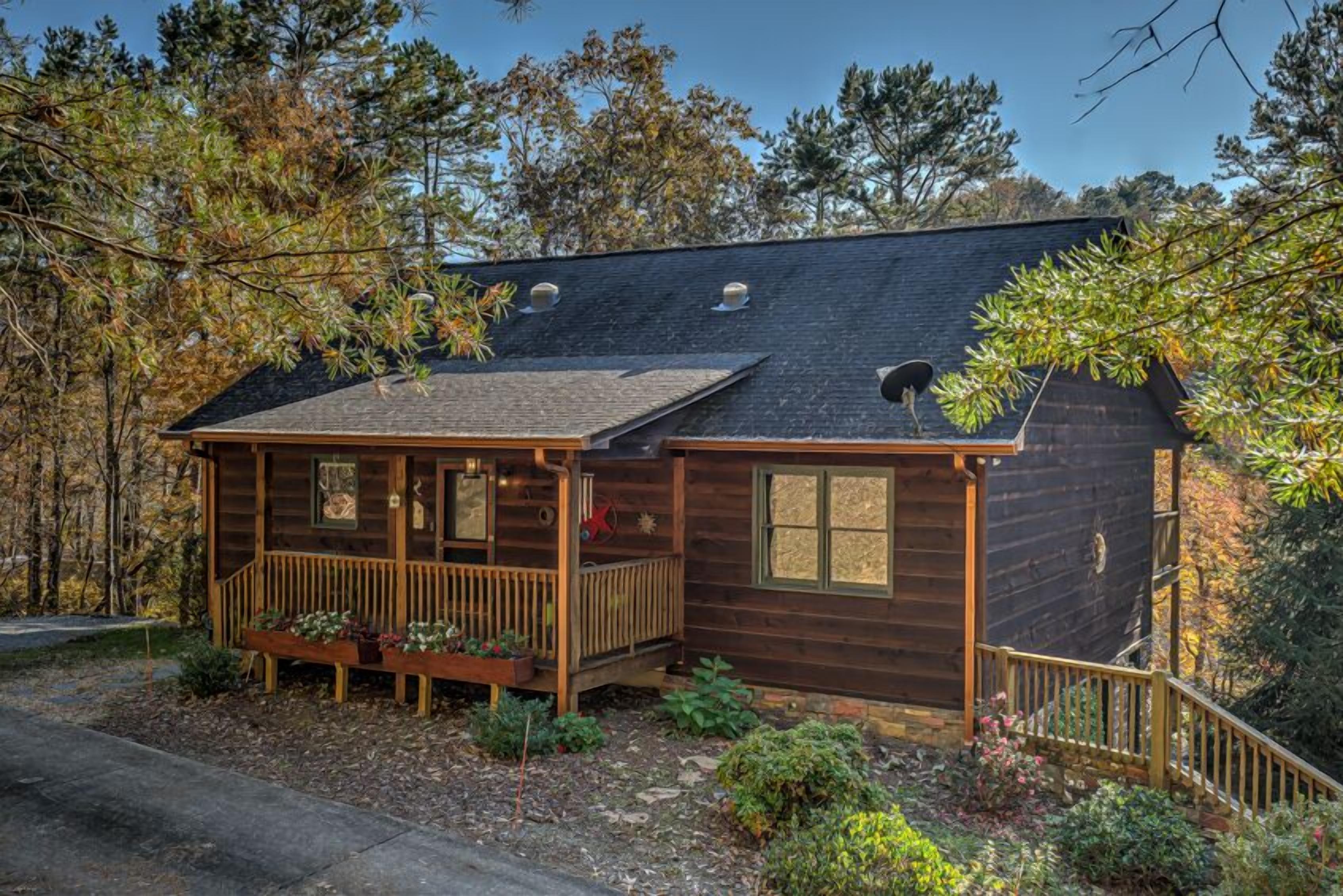 Une cabane rustique dotée d’une terrasse en bois, d’un porche abrité et d’une antenne parabolique.