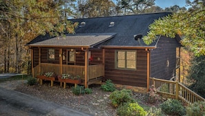 Eine rustikale Holzhütte mit einer Holzterrasse, einer Veranda und einer Satellitenschüssel.