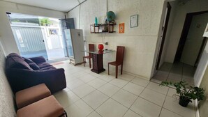 A living area with a sofa, ottoman, and a small table with chairs. There is a globe on a shelf, a potted plant, and a door leading outside. - Casa Recife Pousada (Recife)