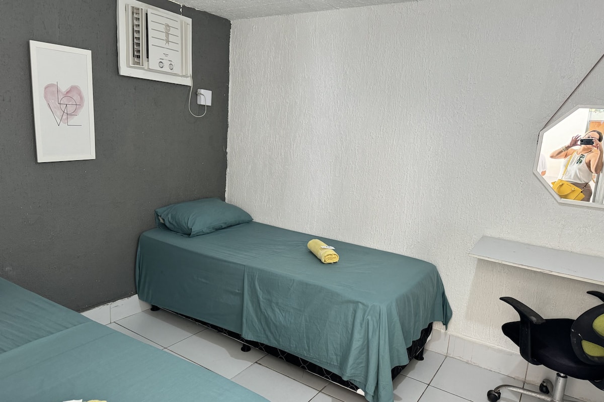 A room with two single beds, a desk, a chair, a mirror, and a framed picture on the wall.