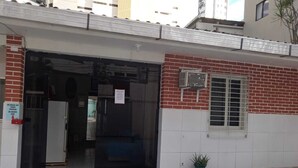 A building entrance with a black door, a small window with metal bars, and a potted plant near the entrance. - Casa Recife Pousada (Recife)