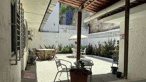 An outdoor patio with a table and chairs, potted plants, and a covered seating area. - Casa Recife Pousada (Recife)