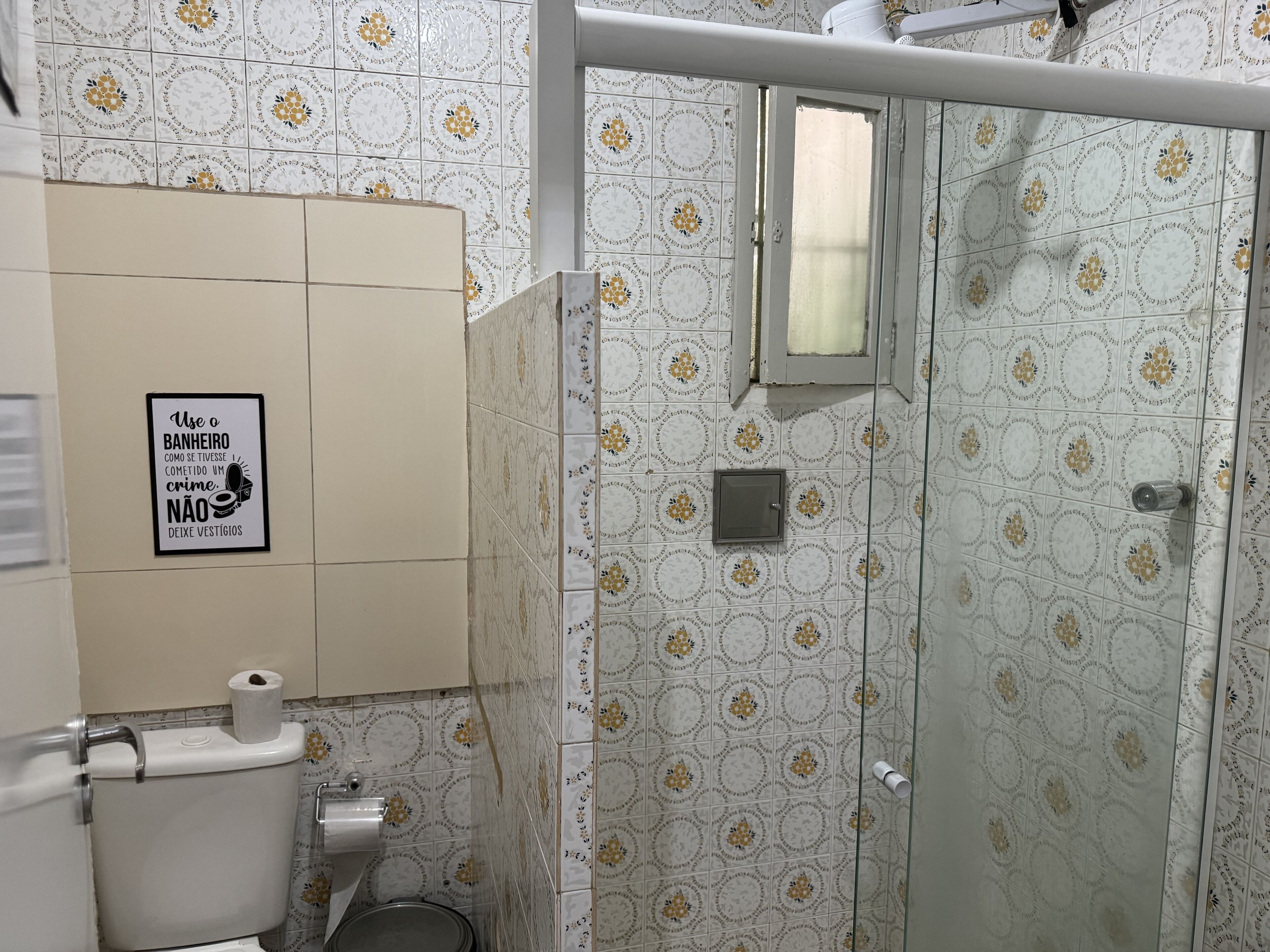 Une salle de bain avec des carreaux décorés, des toilettes, une douche et un panneau sur le mur.