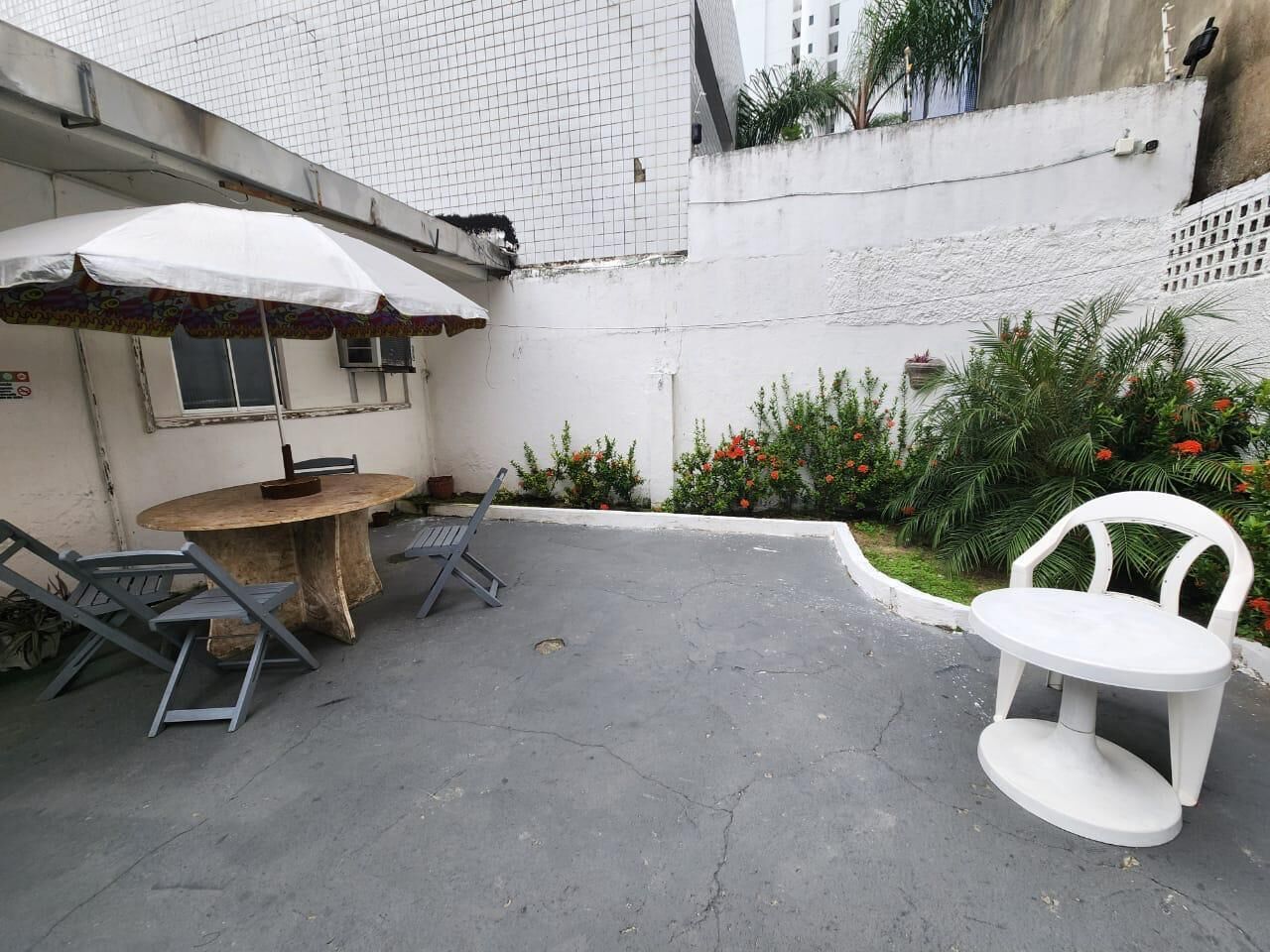 Un patio con una mesa redonda y sillas, una sombrilla blanca y una silla blanca.