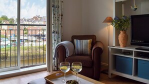 A living room with a sofa, a TV, and a tray with glasses of wine.
