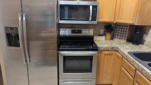 Una cocina con un refrigerador de acero inoxidable, un microondas y un horno.