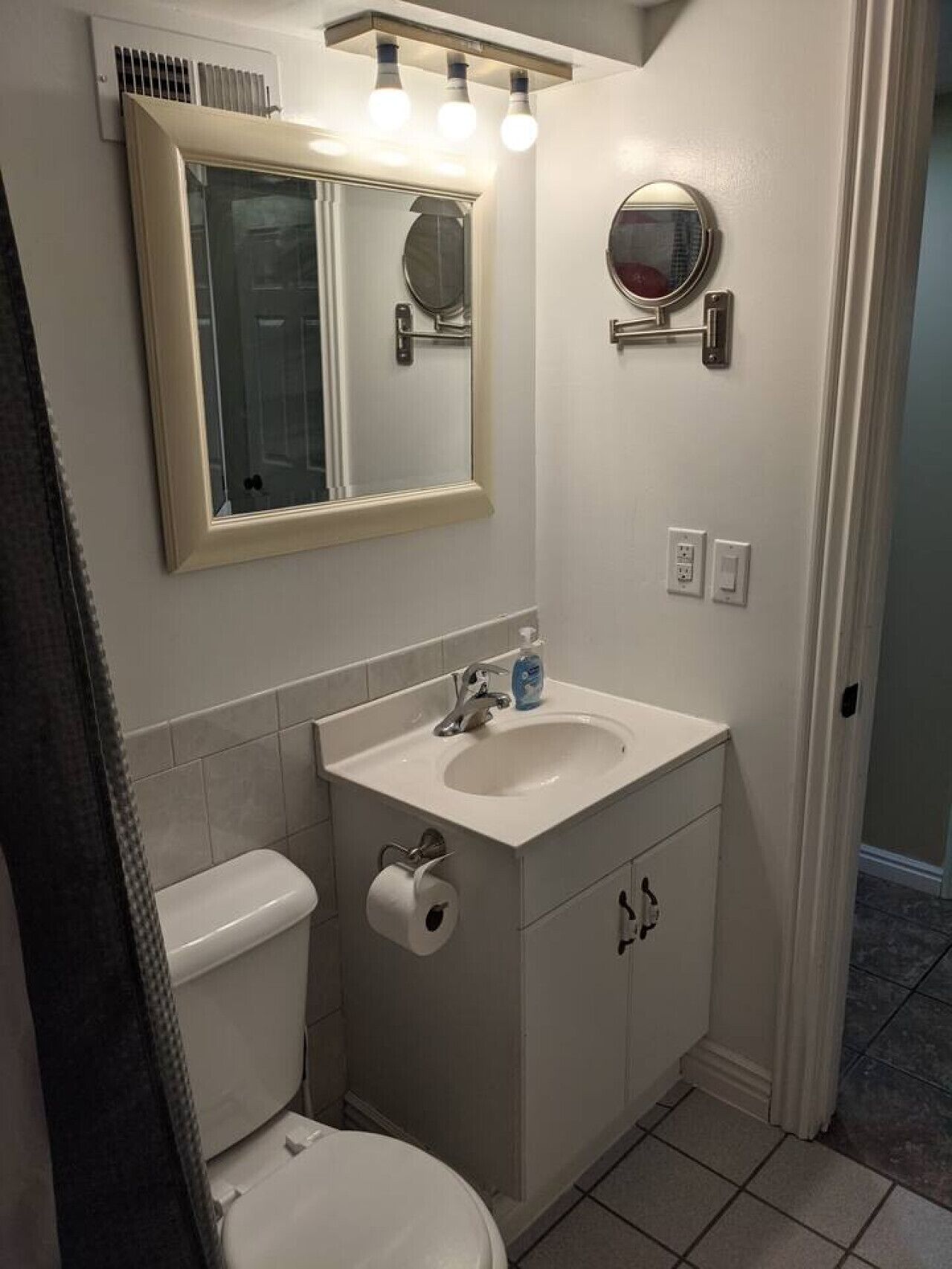 Een badkamer met toilet, wastafel, spiegel en handdoekhouder.