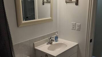 Een badkamer met toilet, wastafel, spiegel en handdoekhouder.