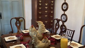A dining table set with plates, glasses, and cutlery, surrounded by wooden chairs. - Inn at 605 (Williamsburg)