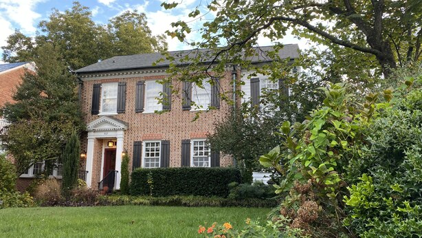 A brick building with a traditional facade, a well-maintained lawn, and various flowering plants. - Inn at 605 (Williamsburg)