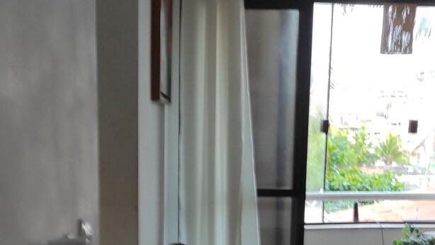Ein Wohnzimmer mit einer Couch, einem Esstisch und einem Fenster mit Vorhängen.