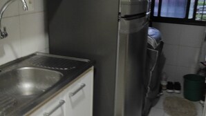 Eine kleine Küche mit einem Edelstahlkühlschrank, einer Spüle und Schränken.