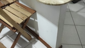 Eine Küche mit Marmorarbeitsplatte, Holzstühlen und einem grauen Sofa.