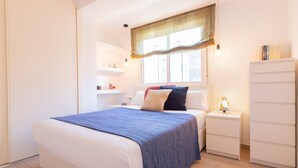 A bedroom with a bed, bedside tables, a nightstand, a wardrobe, and a window with curtains. - SW Mendoza 20 (Málaga)